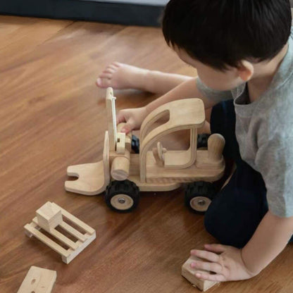 Child playing with PlanToys Forklift on a wooden floor
