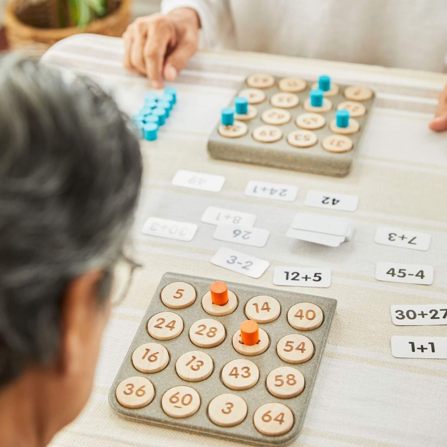 Educational math game with wooden numbers and buttons on a table.