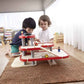 Two children playing with PlanToys Parking Garage on a rug in a room.