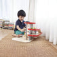 Child playing with PlanToys Parking Garage in a room with books and curtains.