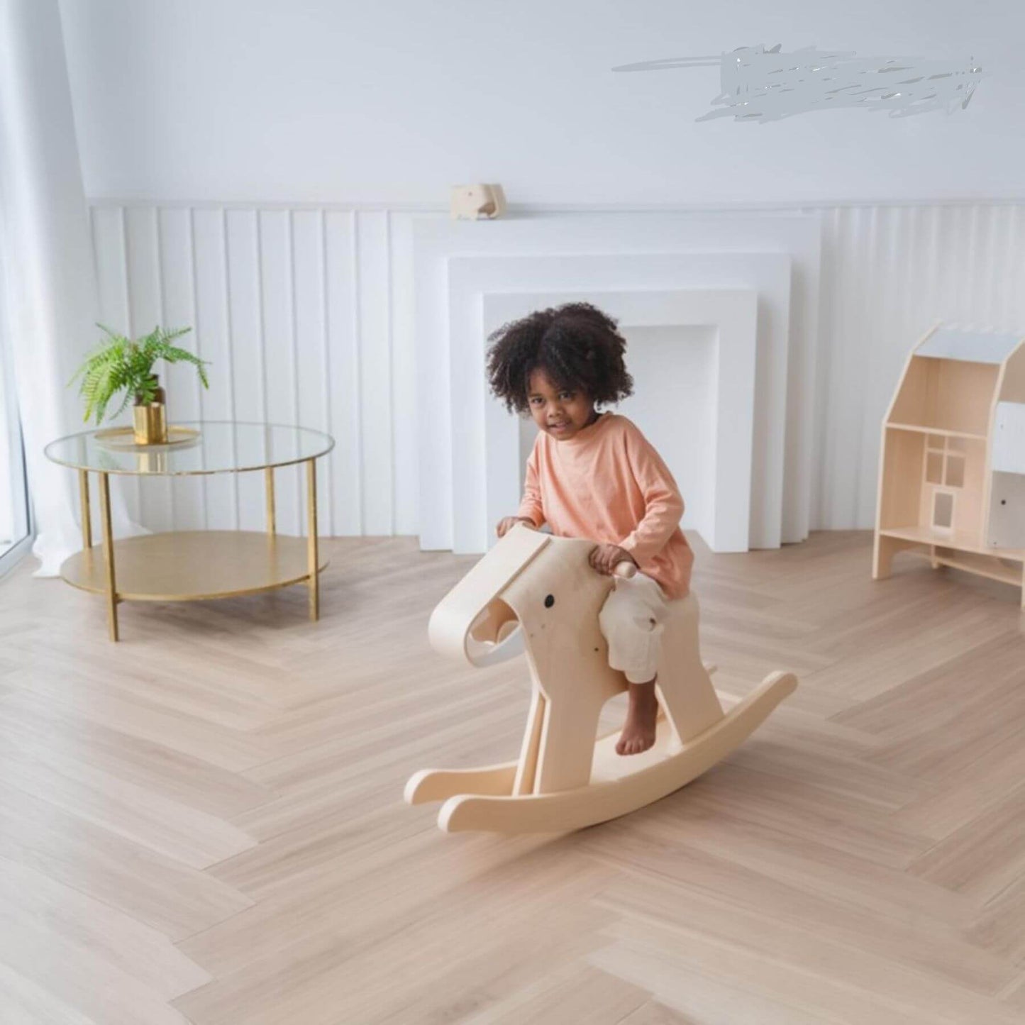 Child on PlanToys Walking Elephant in a bright, minimalistic room with a glass table and plant.
