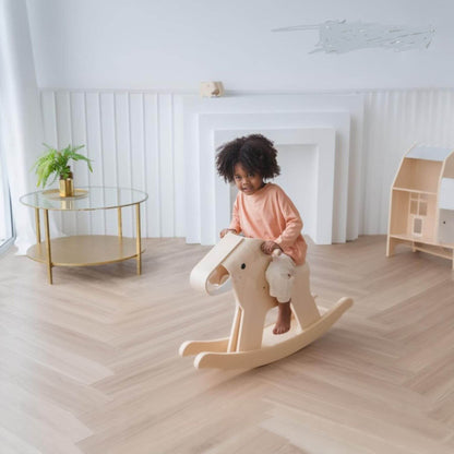 Child on PlanToys Walking Elephant in a bright, minimalistic room with a glass table and plant.
