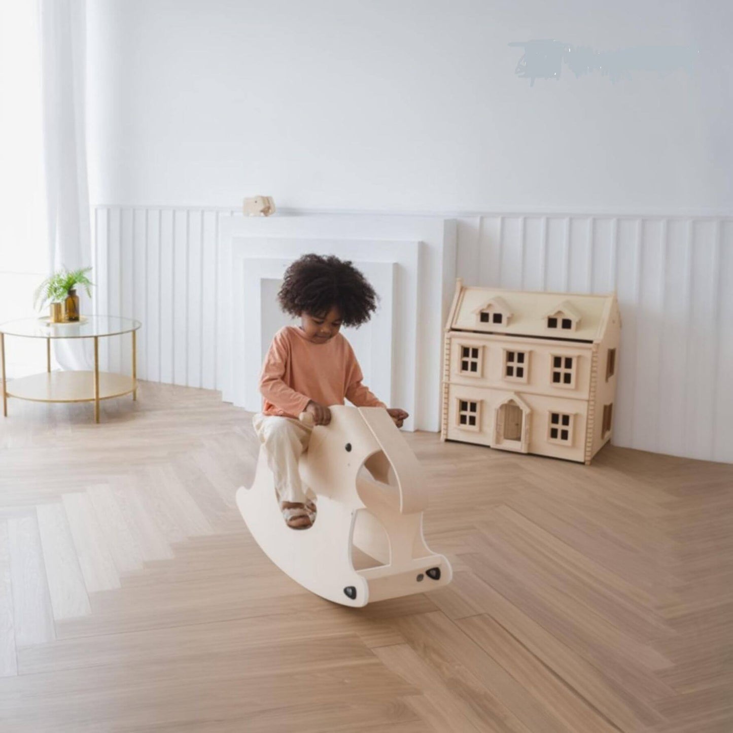 Child playing on PlanToys Walking Elephant in a room with a wooden dollhouse.