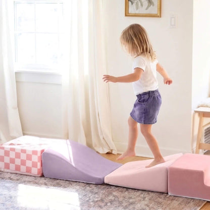 A young child walks across Tiny Land® PlayNest Climbing Blocks - Violet in a bright room.
