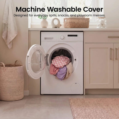 A white front-loading washing machine in a bright laundry room with its door open, showing colorful laundry inside.