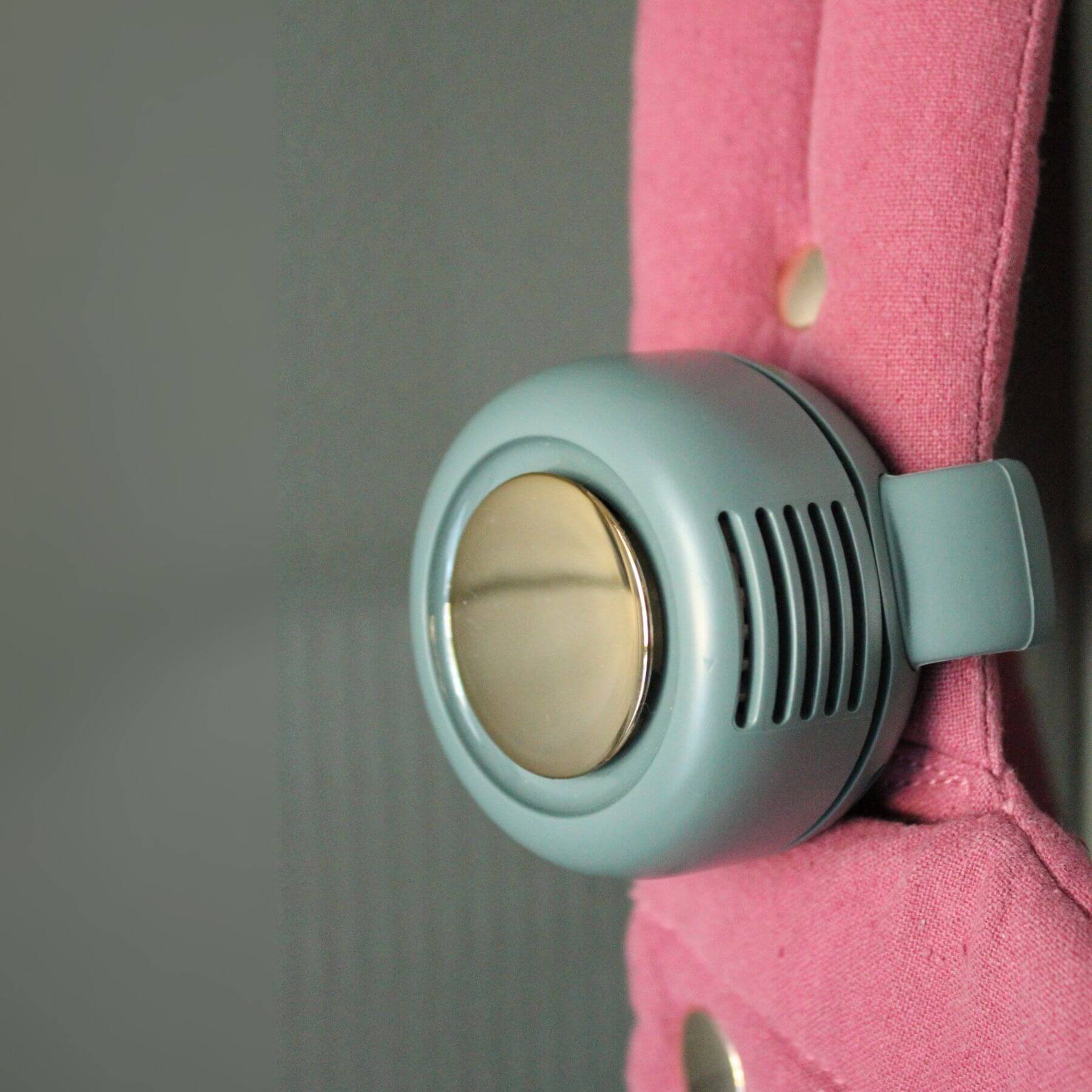 Coco Carriers Portable Rechargeable Fan - Green attached to a pink fabric surface
