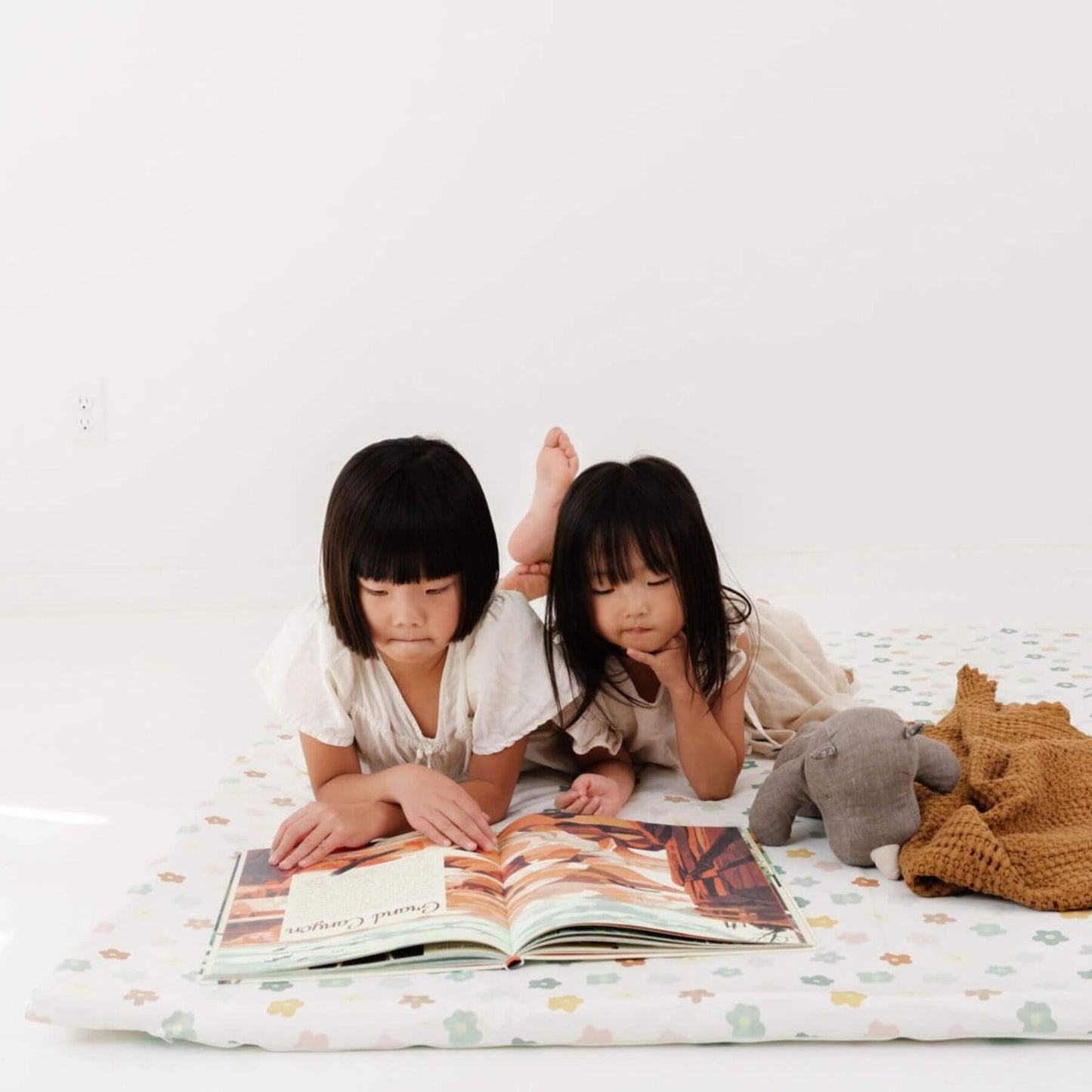 Two children reading a book together on Toki Kids Playful Posies Vegan Leather Mat