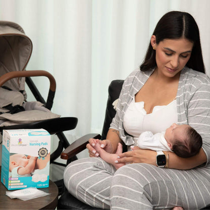 A woman in a gray and white striped nursing outfit holds a baby while sitting in a chair.