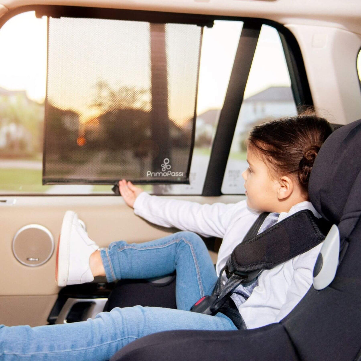 Child in a car seat with a PrimoPassi window shade in a vehicle.
