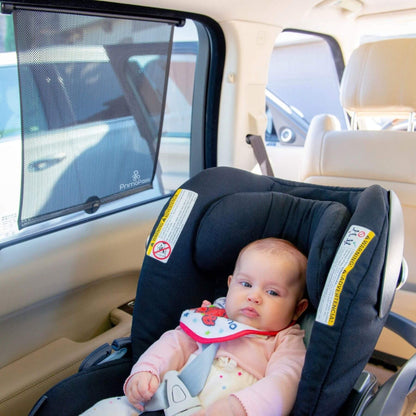 Baby in a car seat with a car window shade in a vehicle
