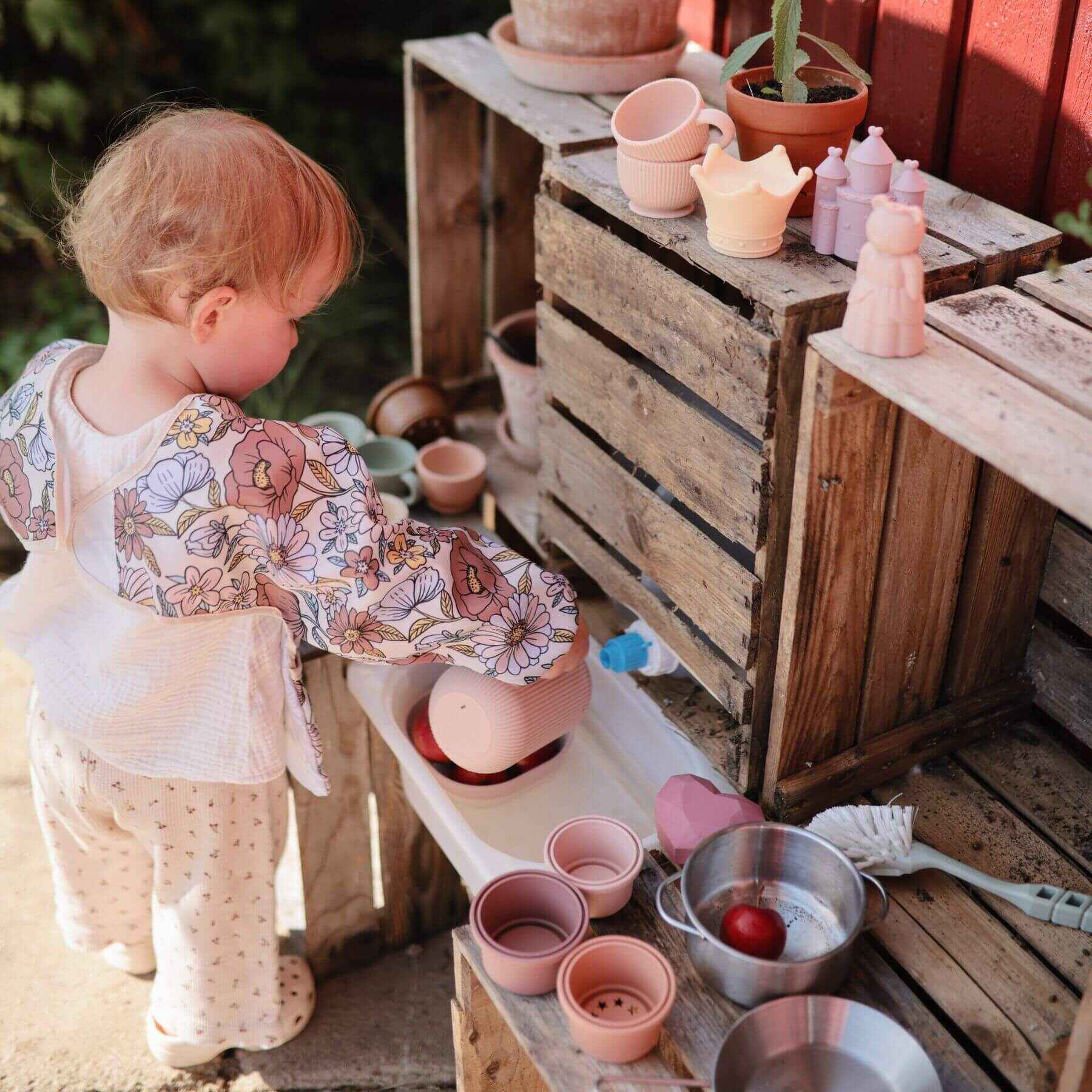 Child playing with ceramic items on a wooden surface outdoors