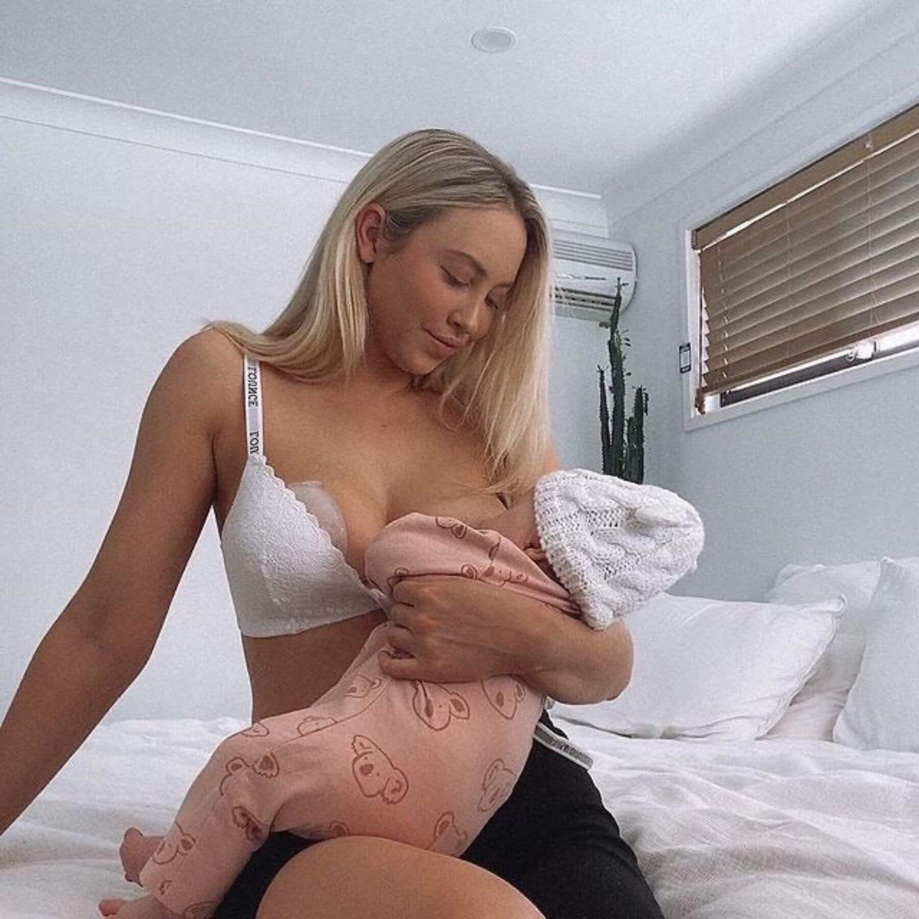 Woman breastfeeding a baby in a bedroom setting
