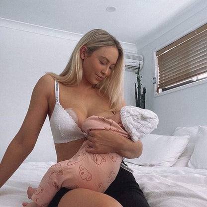 Woman breastfeeding a baby in a bedroom setting