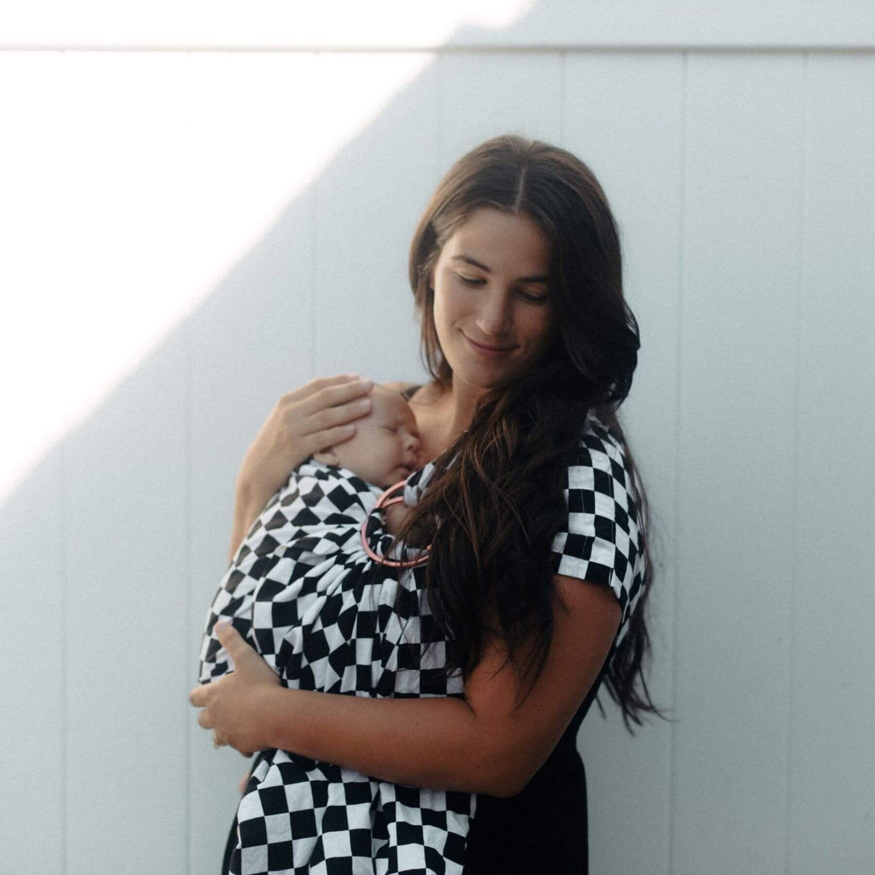 Woman holding a baby wrapped in Little Mae & Co Race Ring Sling Carrier