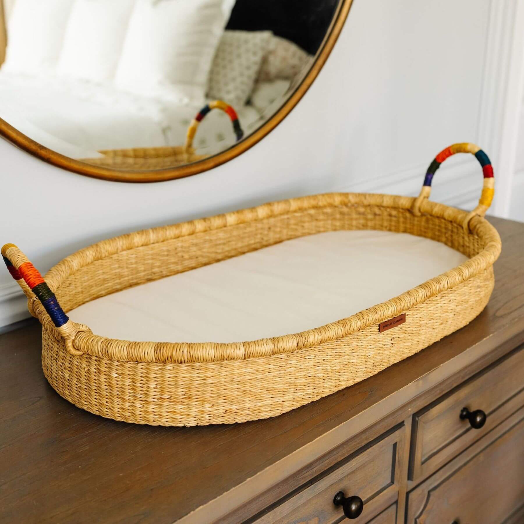 Plum+Sparrow Rainbow Handle Changing Basket on a wooden dresser