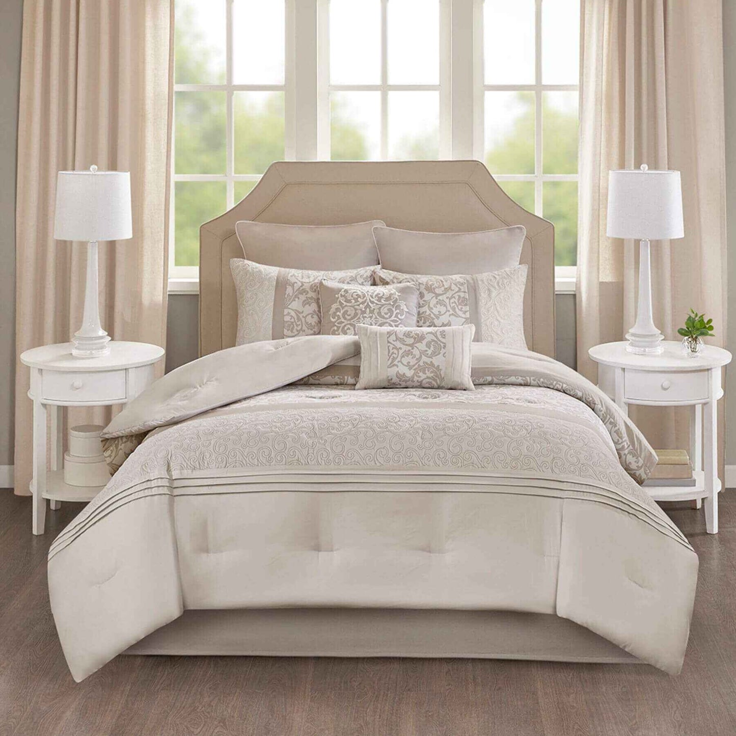 Neatly made Ramsey Embroidered 8 Piece Comforter Set Neutral in a bedroom setting with two lamps on nightstands.