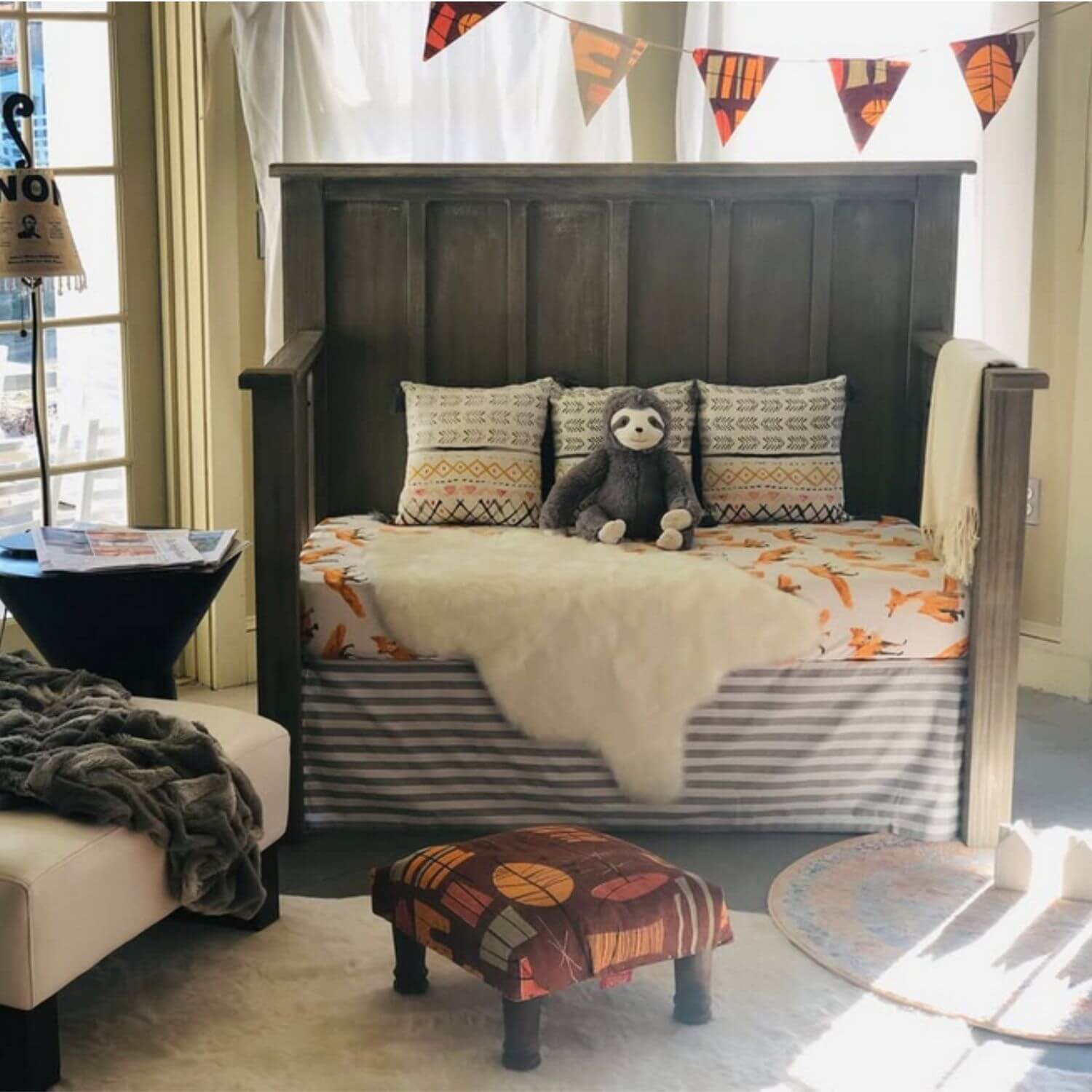 Children's bedroom with a bed, ottoman, and decorative pillows.