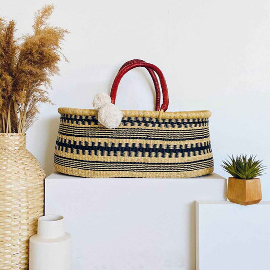 Plum+Sparrow Remy No Hood African Moses Basket on a white surface, surrounded by decorative items.