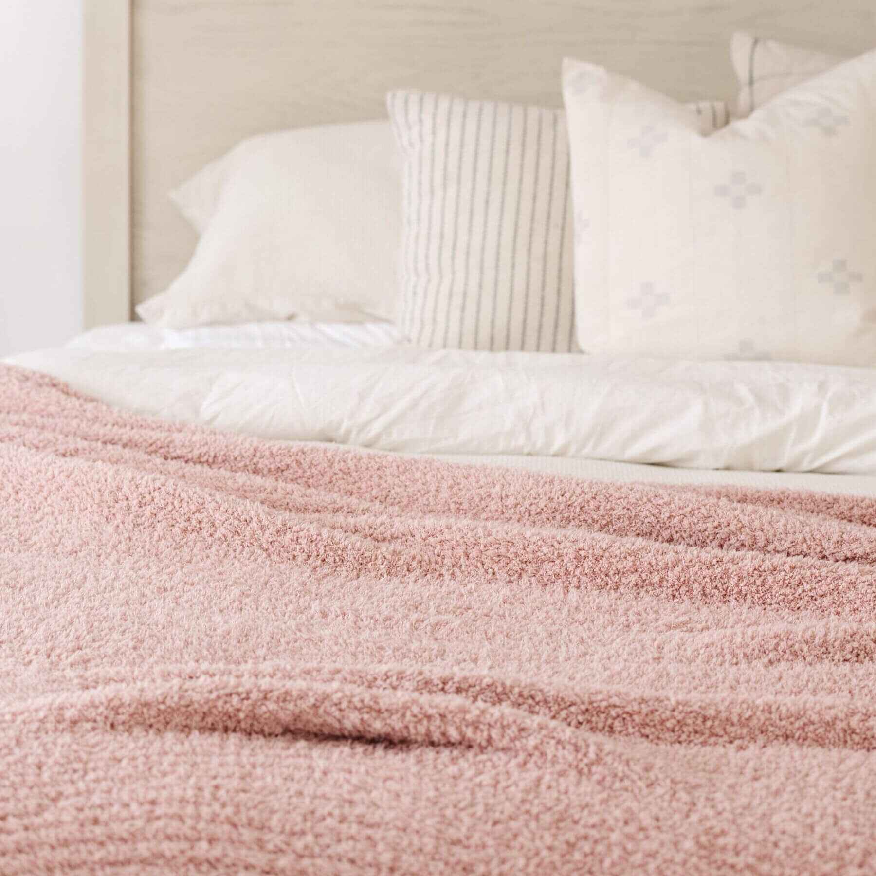 Bed with Saranoni Ribbed Bamboni® XL Blanket - Cameo and white pillows in a bedroom setting