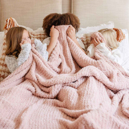 Three people wrapped in Saranoni Ribbed Bamboni® XL Blanket - Cameo on a bed