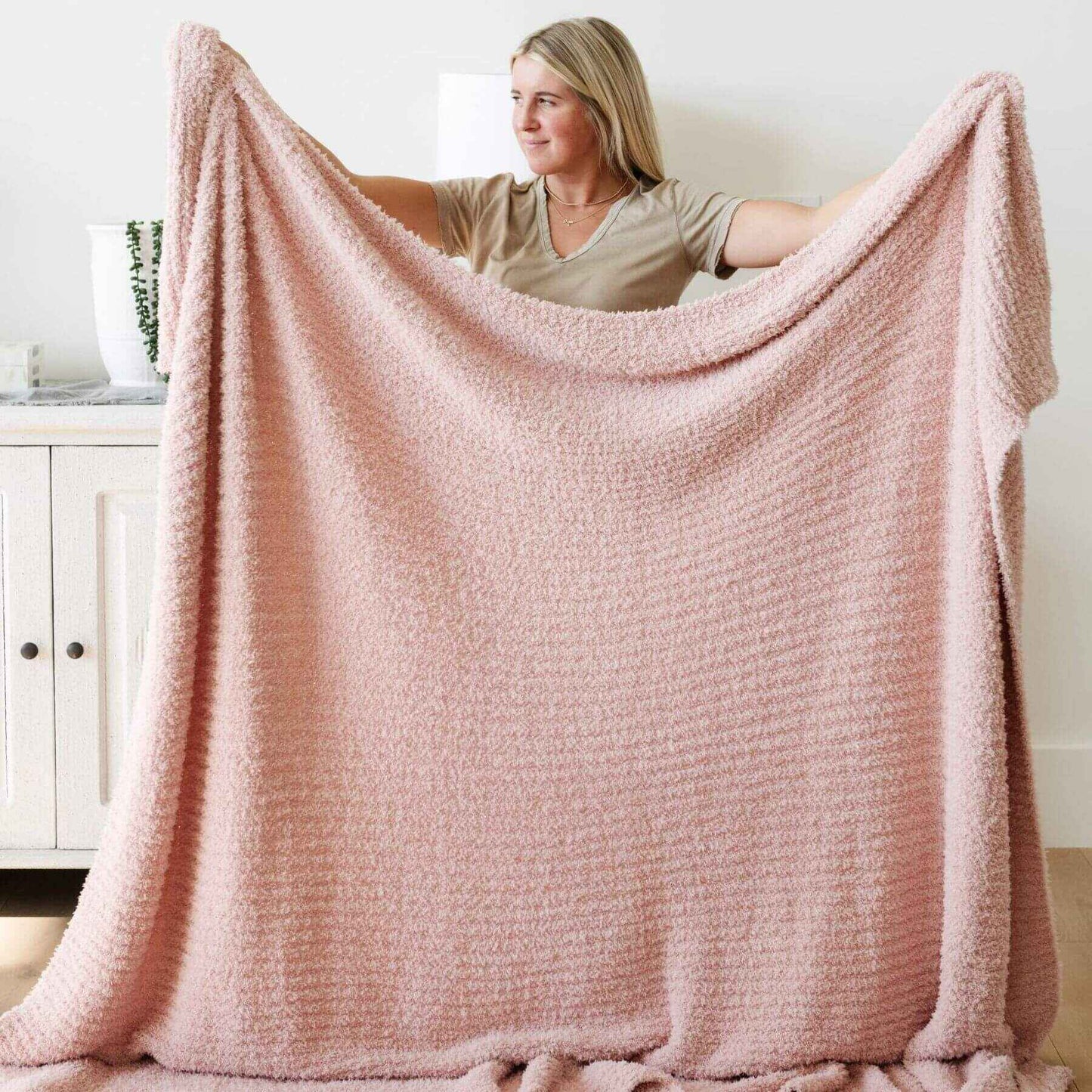 Woman holding Saranoni Ribbed Bamboni® XL Blanket - Cameo in a room with white walls and a white cabinet.