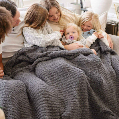 Family of five snuggling under Saranoni Ribbed Bamboni® XL Blanket - Charcoal in a cozy living room.
