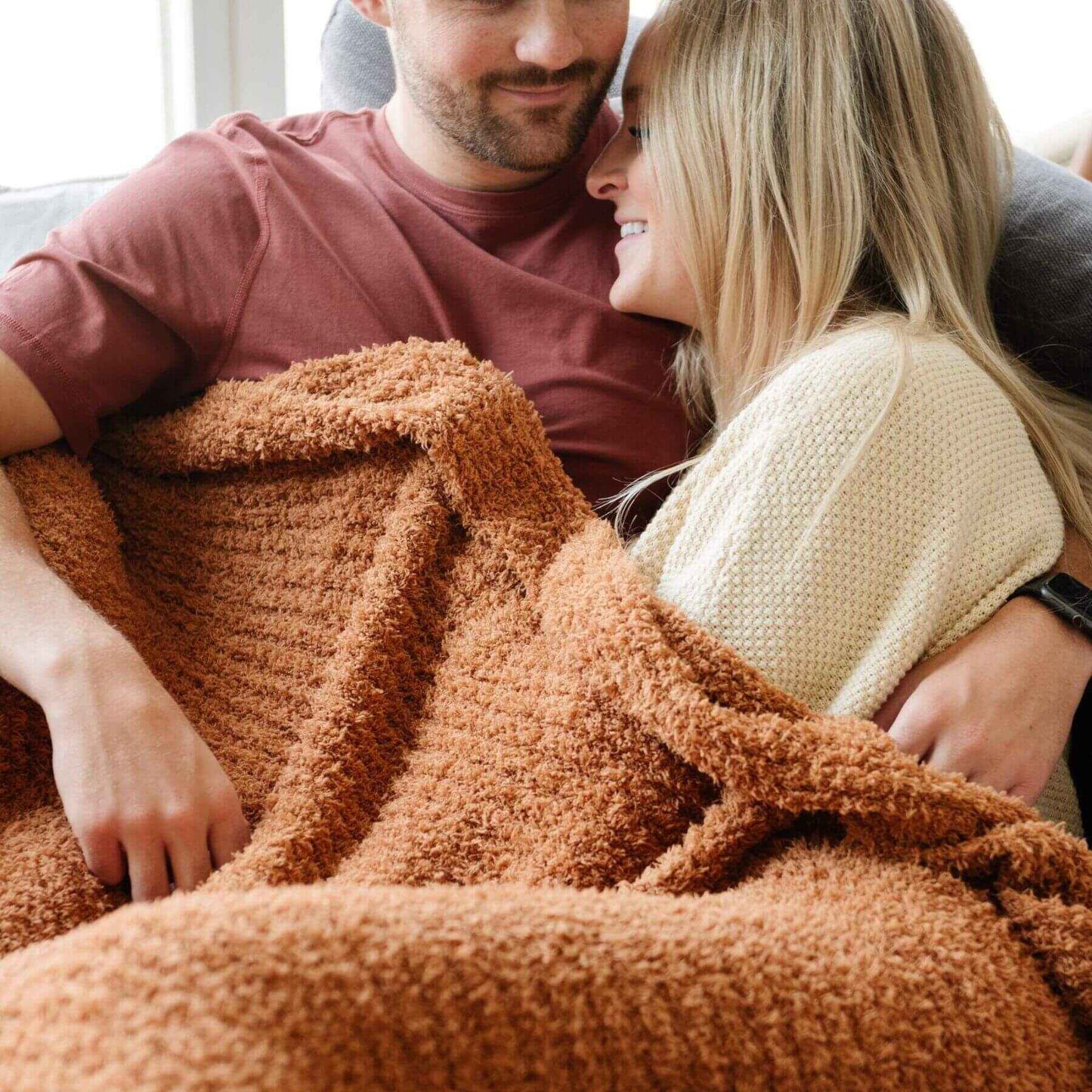 Couple sitting together under Saranoni Ribbed Bamboni® XL Blanket - Ginger in a cozy indoor setting.