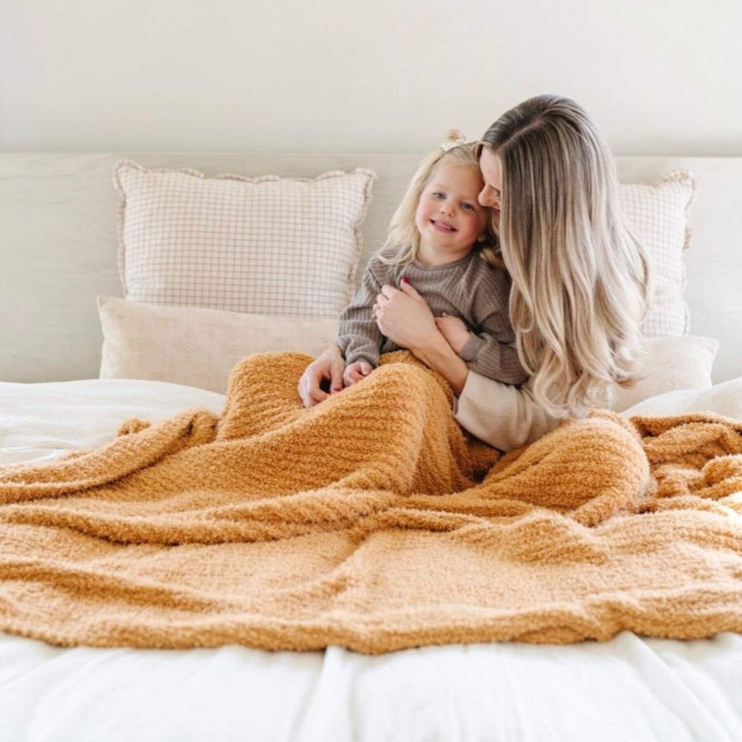 Woman and child sitting on a bed under Saranoni Ribbed Bamboni® XL Blanket - Golden