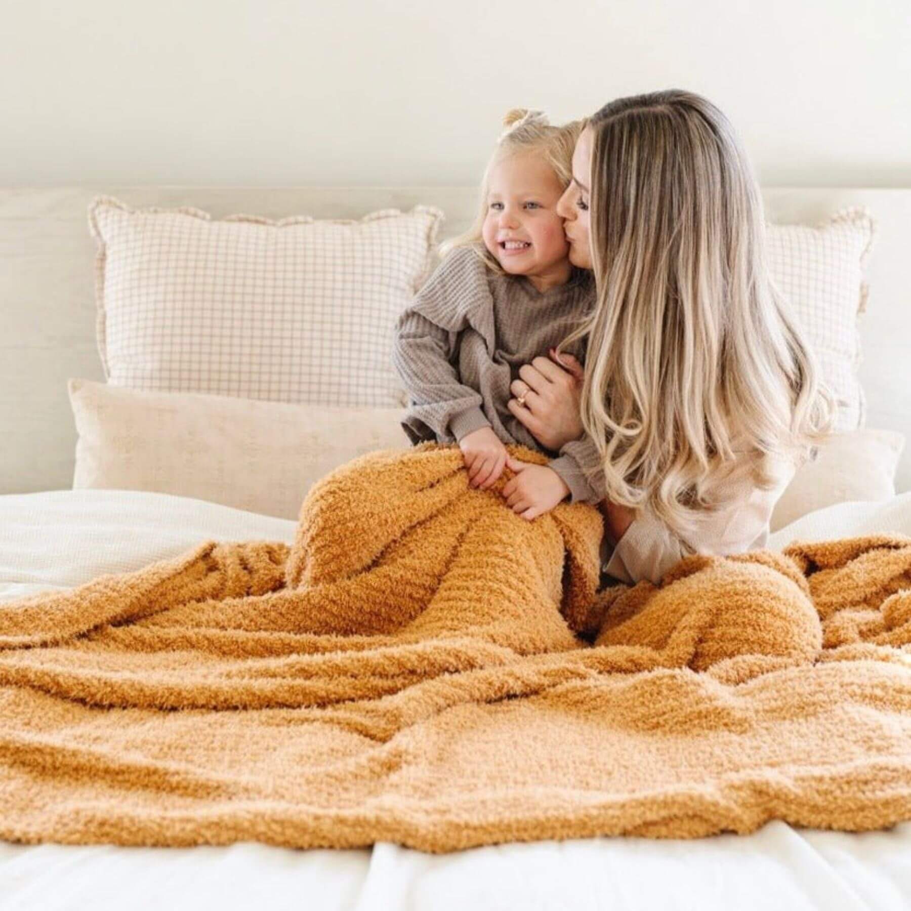 Woman holding a child on a bed with Saranoni Ribbed Bamboni® XL Blanket - Golden