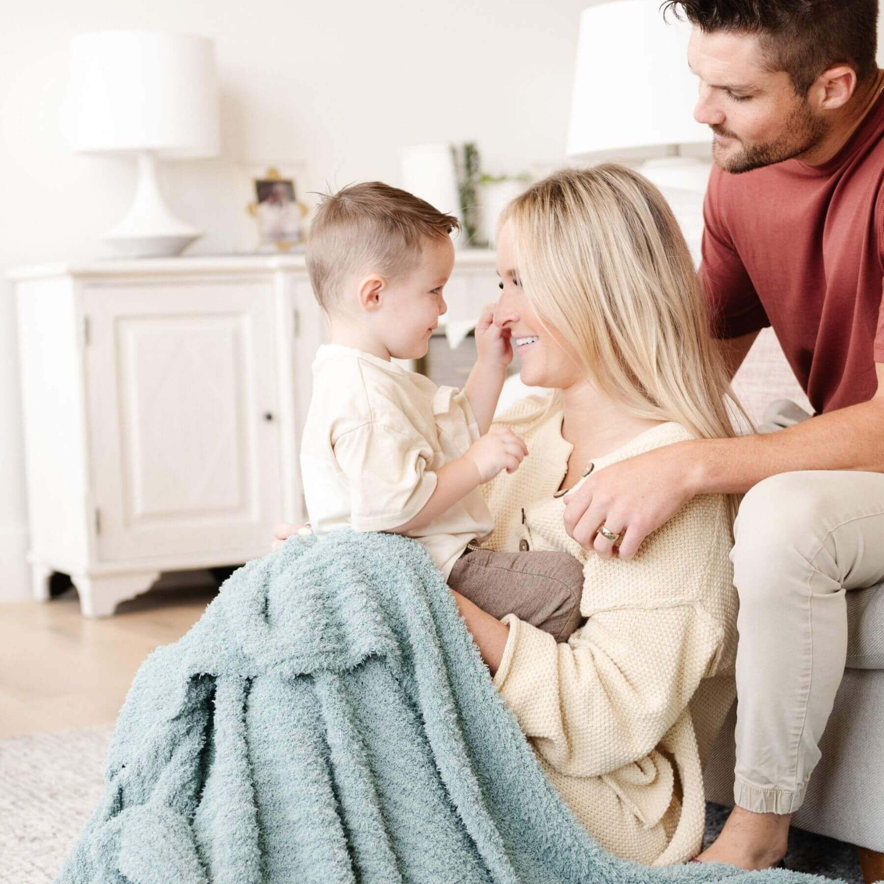 Family sitting together on a couch with Saranoni Ribbed Bamboni® XL Blanket - Surf, smiling and interacting.