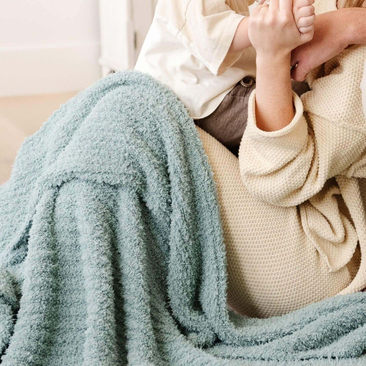 Person wrapped in Saranoni Ribbed Bamboni® XL Blanket - Surf sitting on a couch