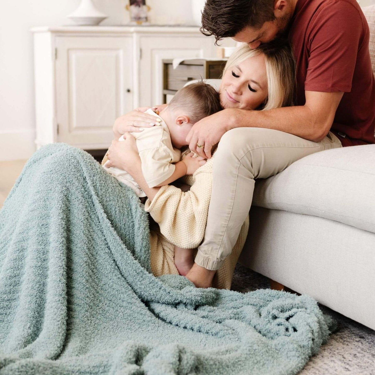 Family of four snuggling on a couch with Saranoni Ribbed Bamboni® XL Blanket - Surf