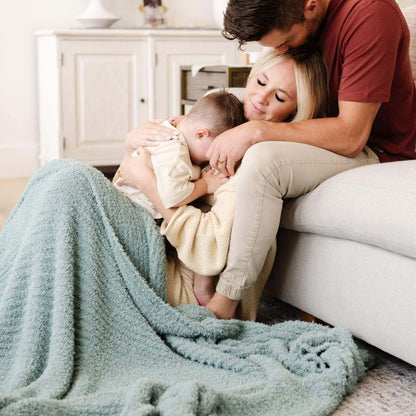 Family of four snuggling on a couch with Saranoni Ribbed Bamboni® XL Blanket - Surf