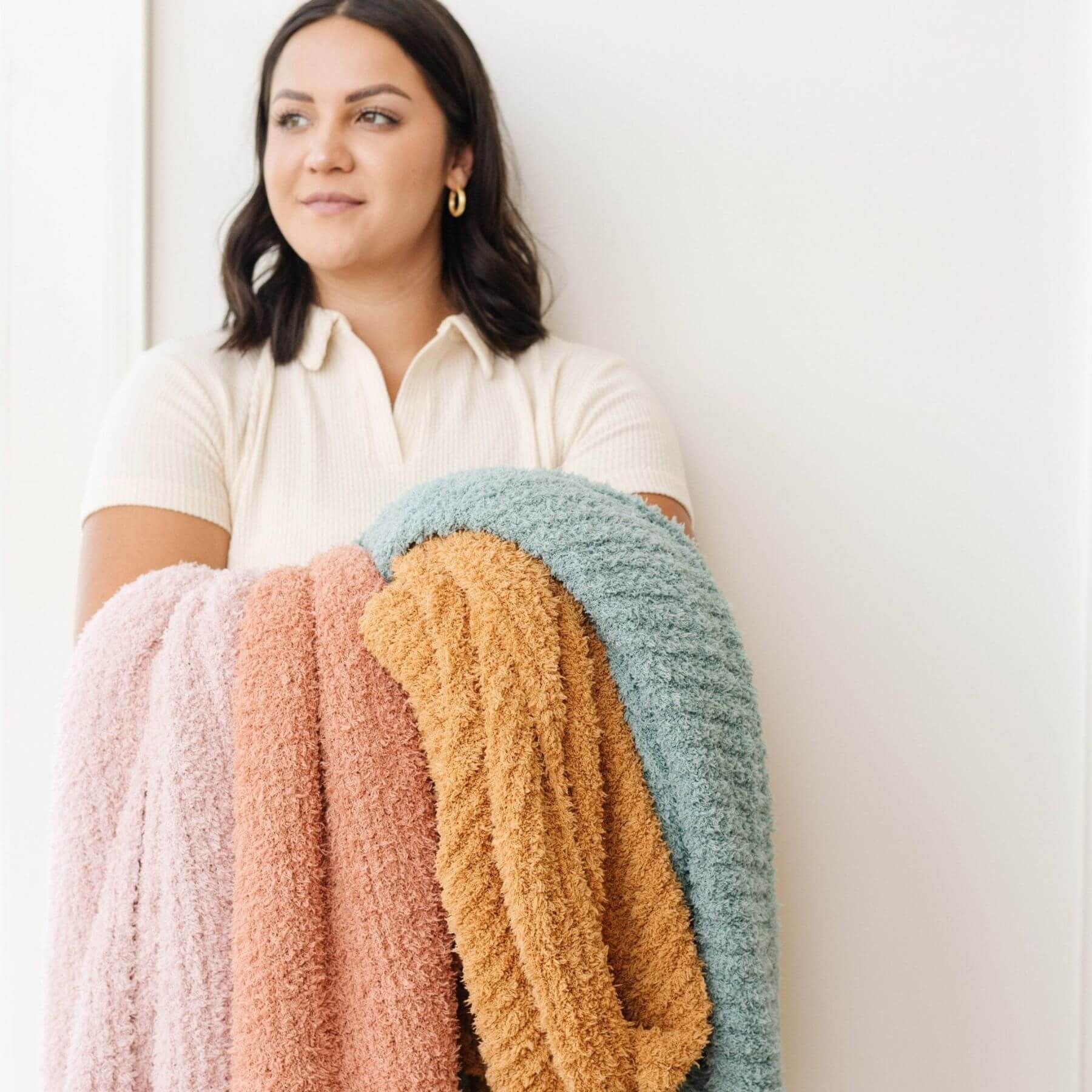 Woman holding a stack of Saranoni Ribbed Bamboni® XL Blankets against a white background
