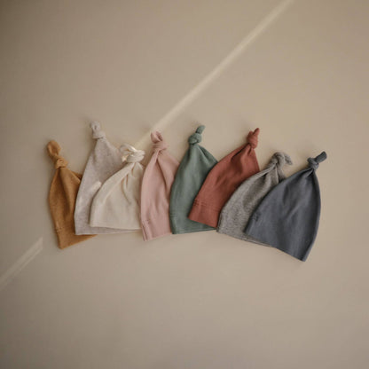 Set of six baby hats in various colors on a neutral background