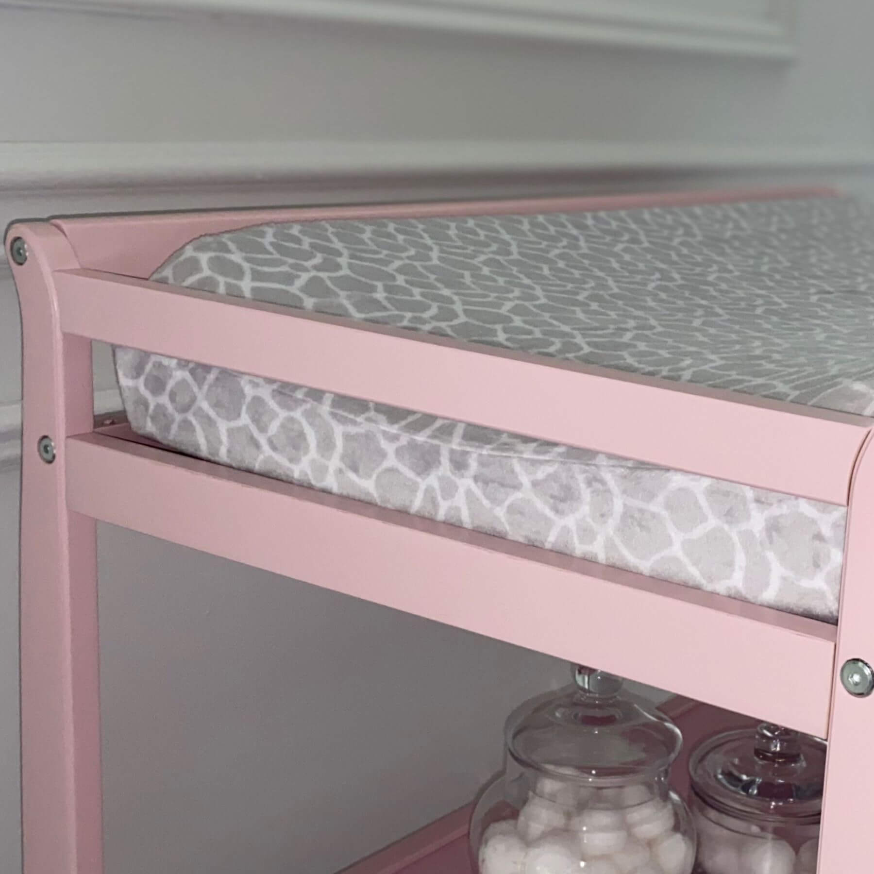 Riley Changing Table Pink with a gray patterned cushion on a white background