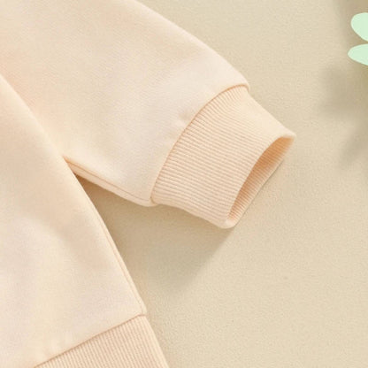 Close-up of a beige sweater with ribbed cuffs on a light green background