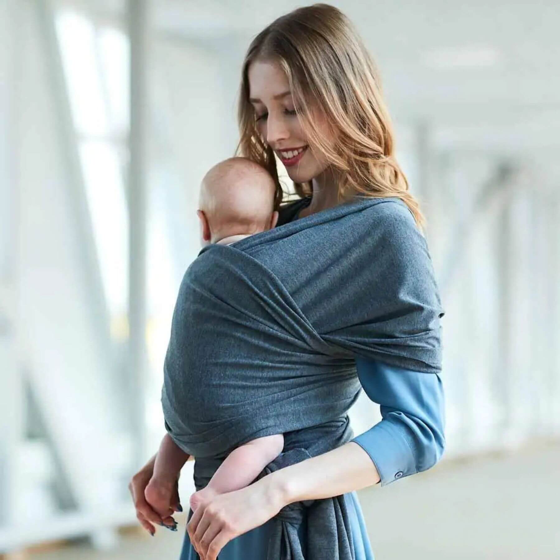 Woman holding a baby in RocketBaby USA Cotton Baby Wrap against a blurred indoor background