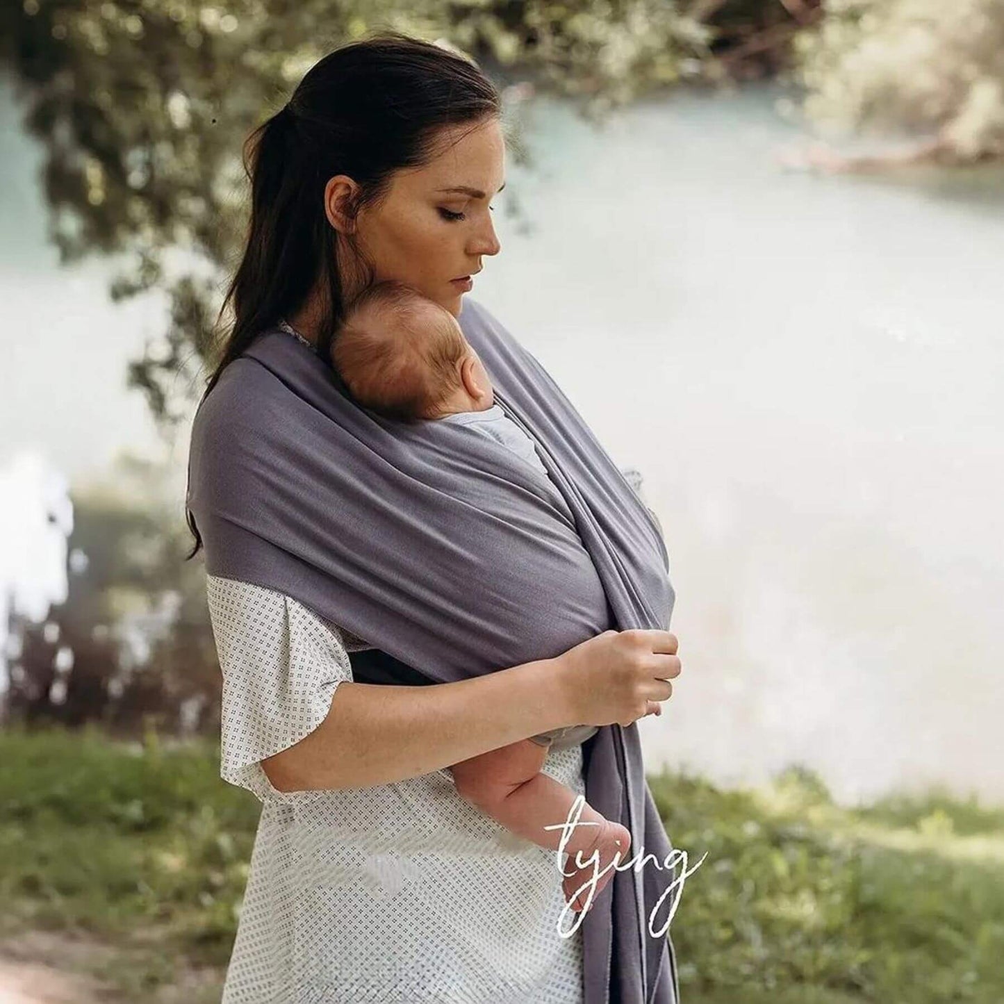 Woman holding a baby in RocketBaby USA Cotton Baby Wrap outdoors near a body of water
