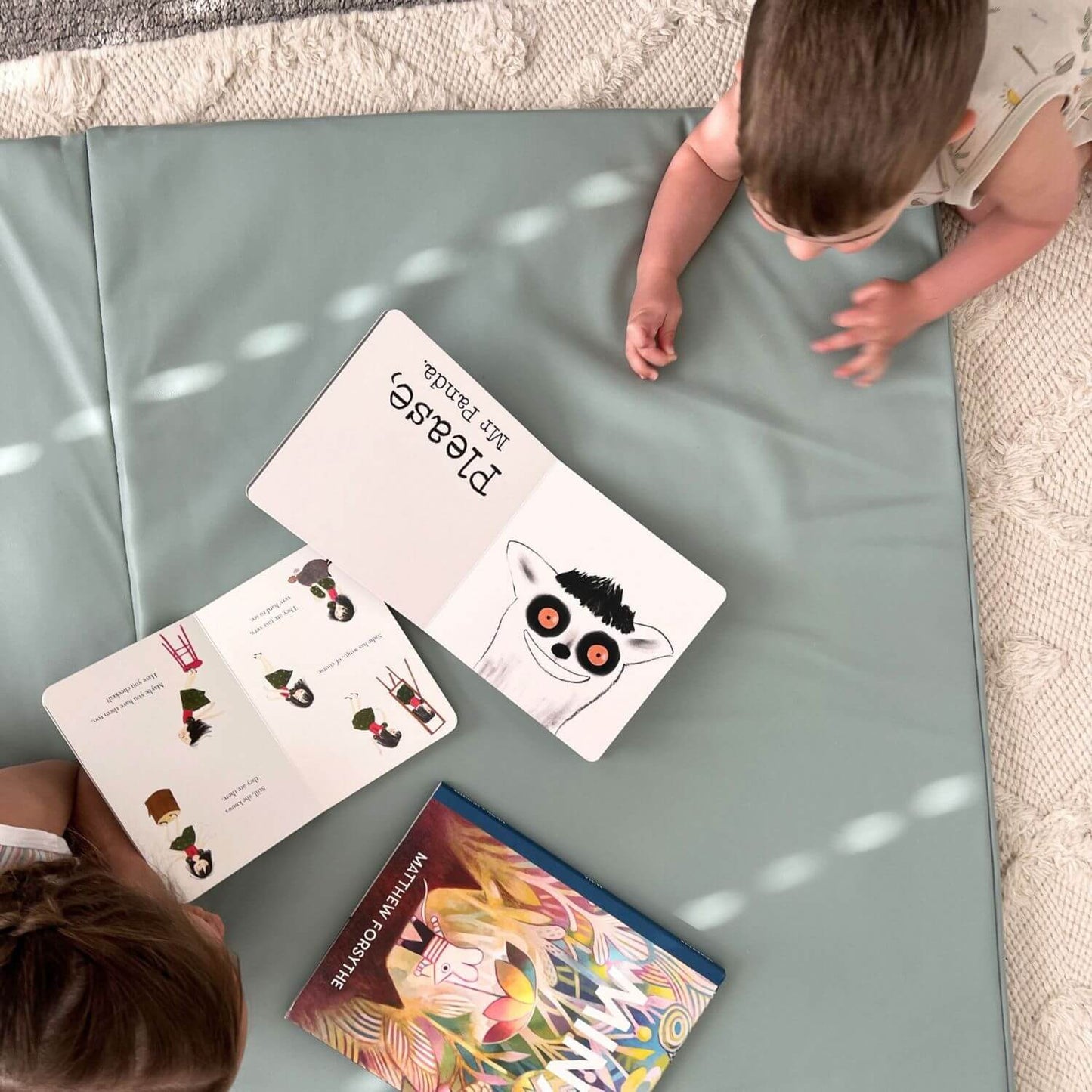 Two children looking at educational books on Toki Kids Sage Vegan Leather Mat