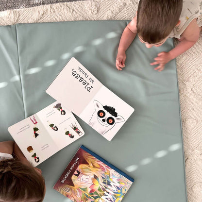 Two children looking at educational books on Toki Kids Sage Vegan Leather Mat