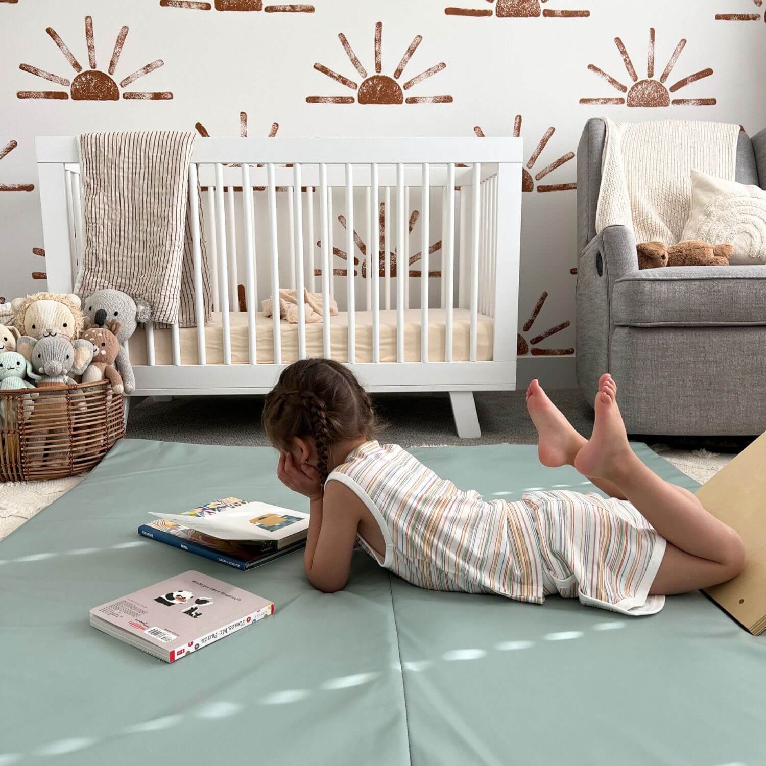 Child lying on Toki Kids Sage Vegan Leather Mat with books and toys in a nursery.