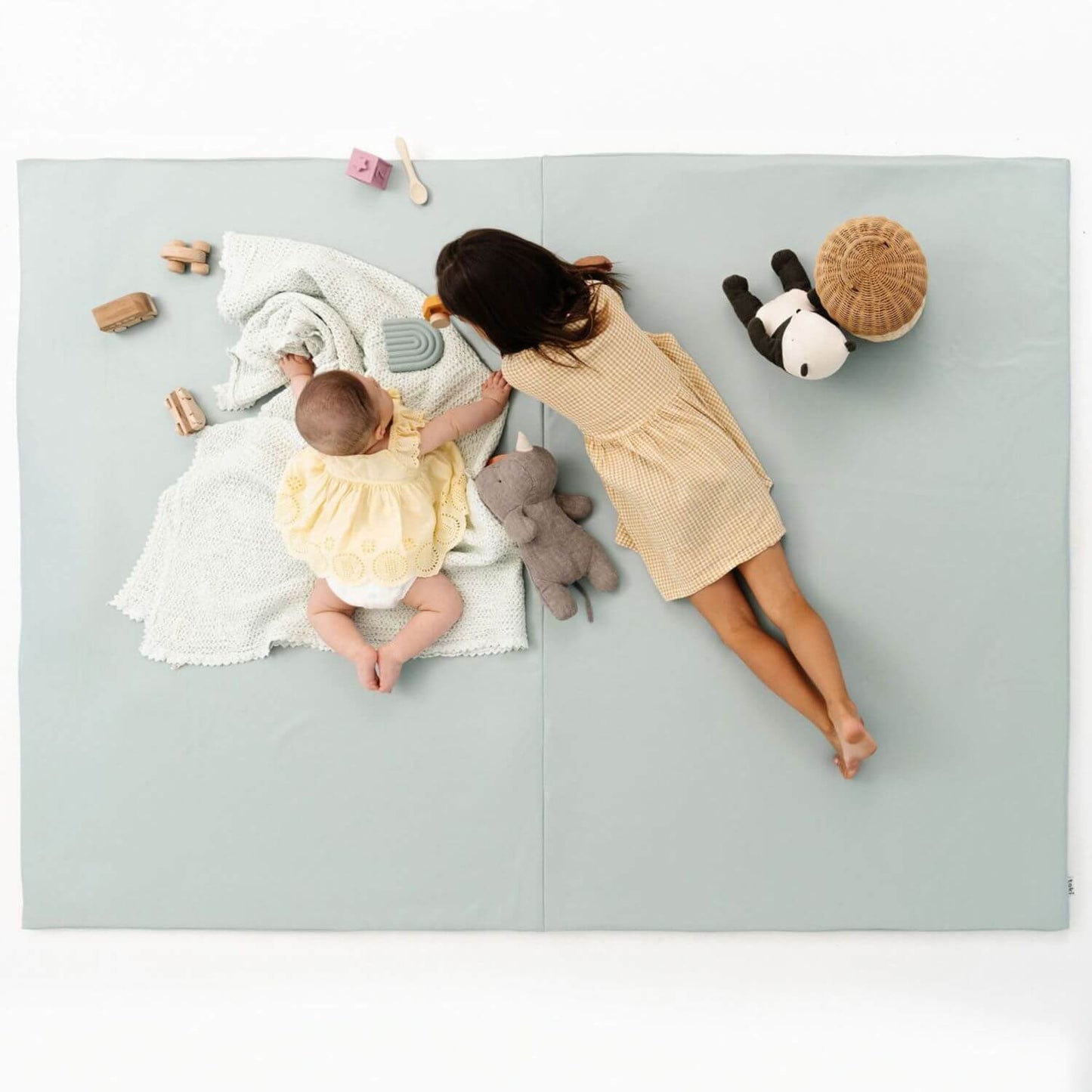 Two children playing with toys on Toki Kids Sage Vegan Leather Mat