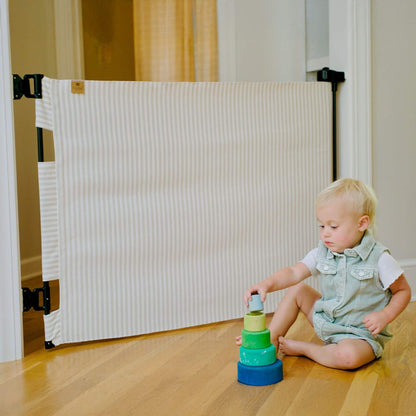 Child playing with a stack of colorful toys near a baby gate.