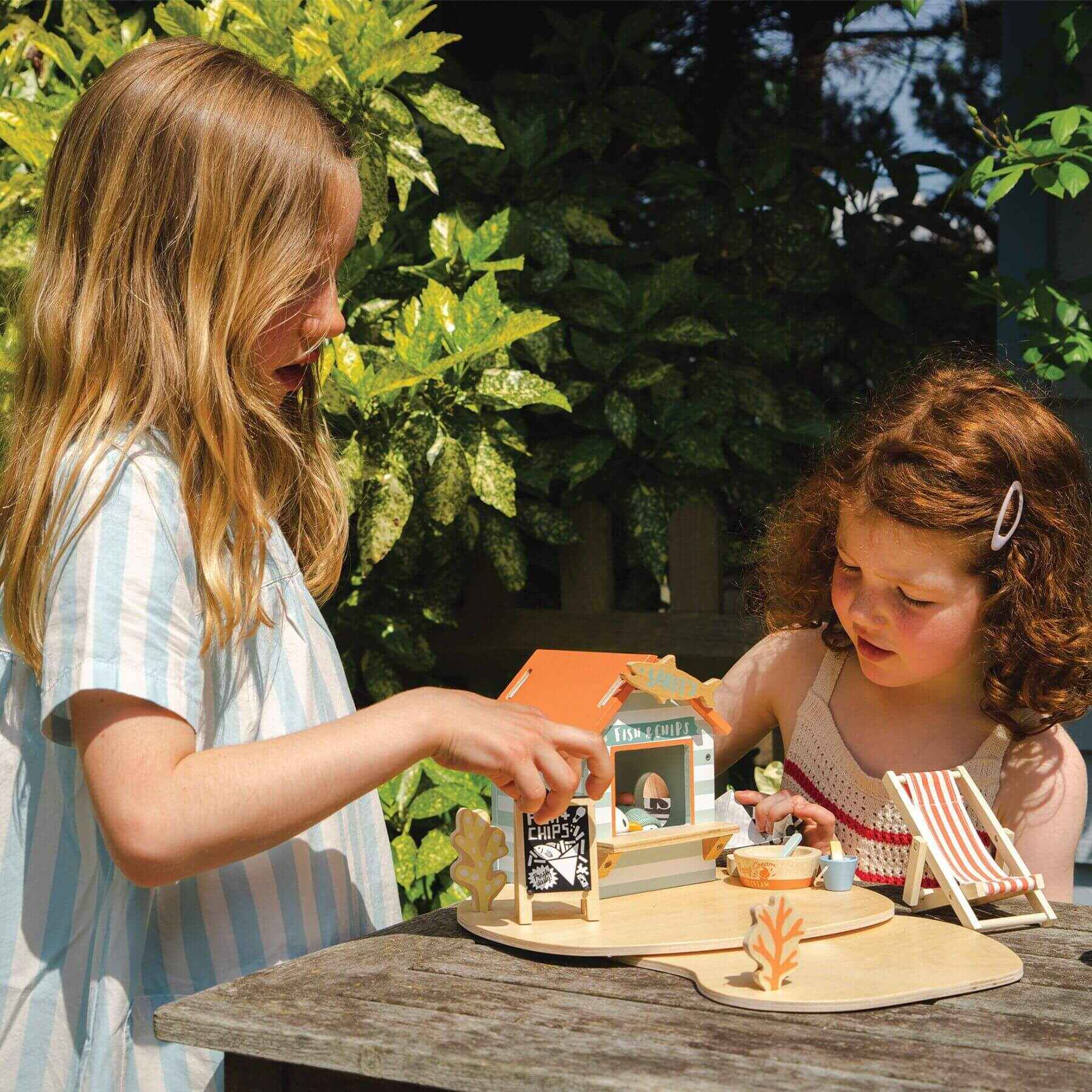 Two children playing with Tender Leaf Sandy's Beach Hut outdoors.