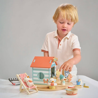Child playing with Tender Leaf Sandy's Beach Hut on a white surface.