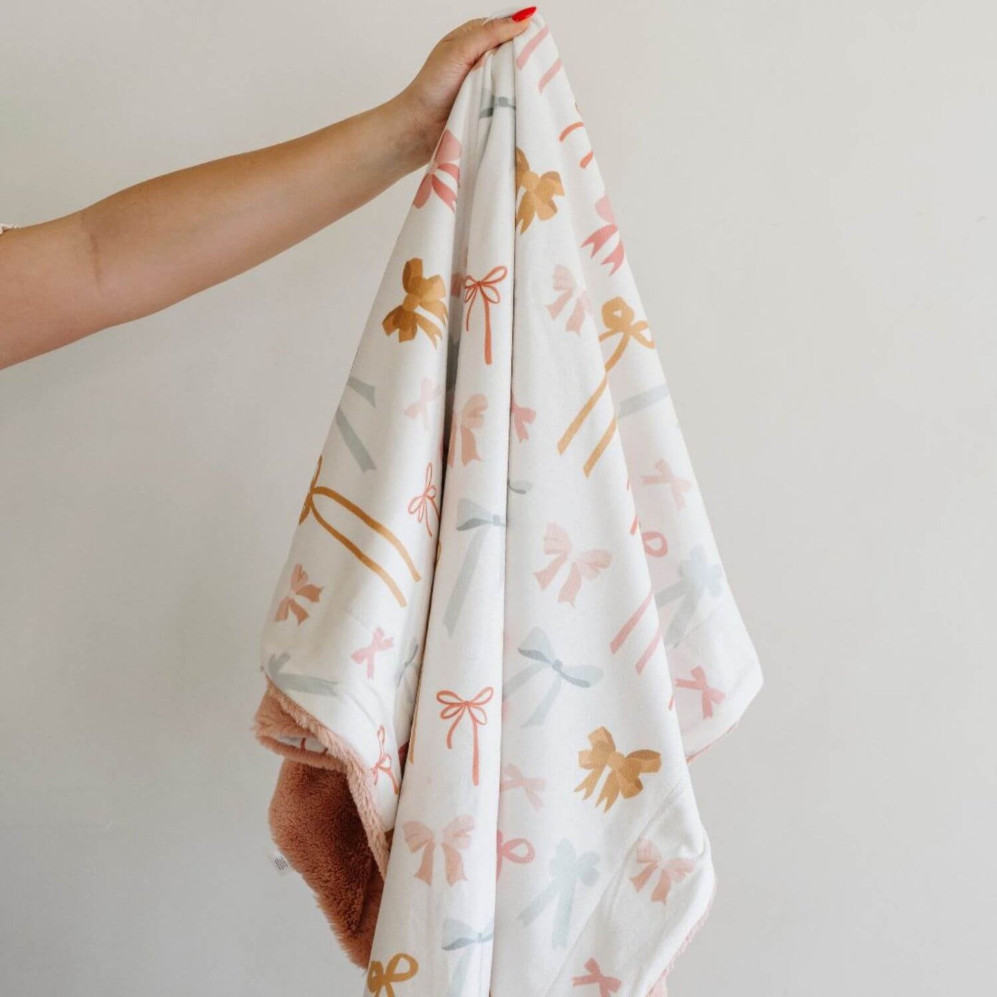 Saranoni Minky/Lush Receiving Blanket Bows held by a hand