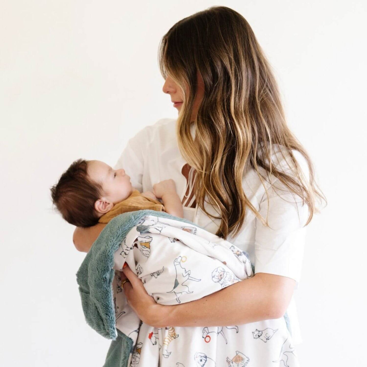 Woman holding a baby wrapped with Saranoni Minky/Lush Receiving Blanket Dog