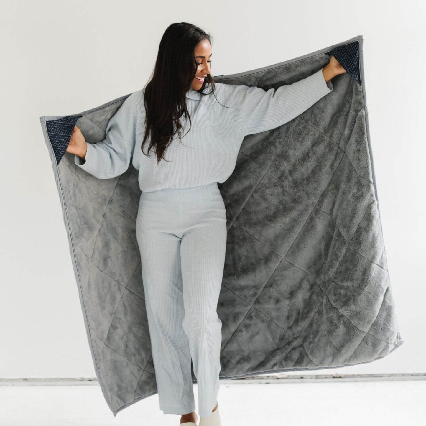 Woman holding Saranoni Outdoor Blanket against a white background