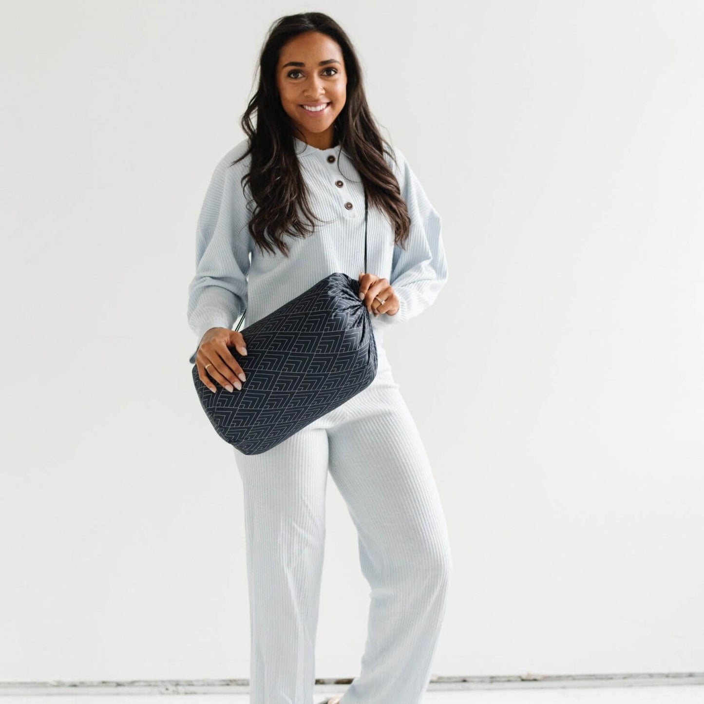 Woman holding a black quilted handbag against a white background